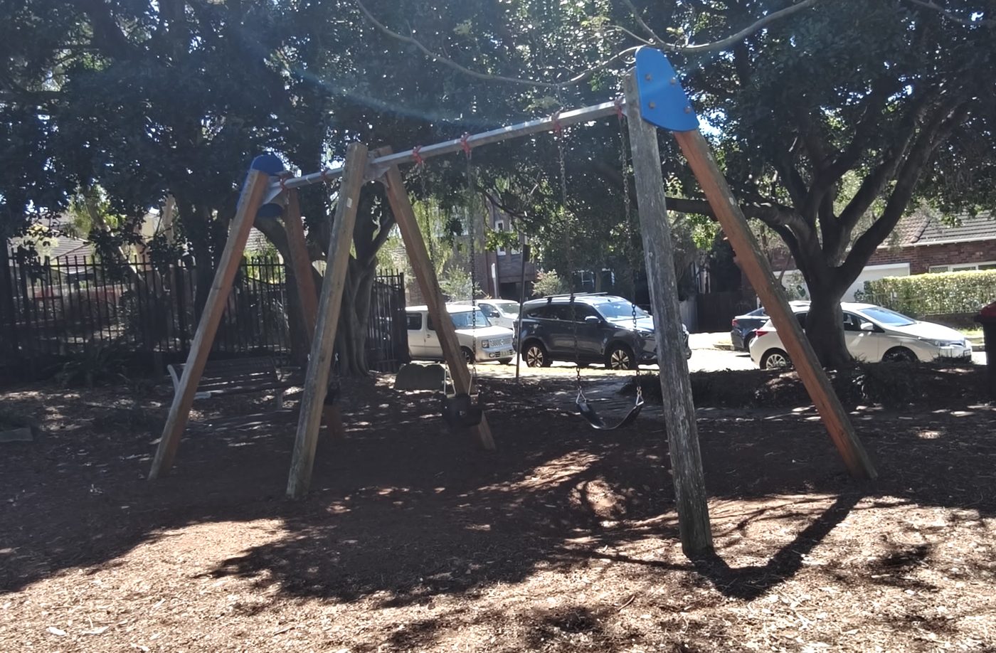 The swings, with parked cars on the street a few metres behind them